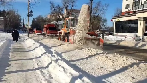 На улице Богдана Хмельницкого работает ротор: он оперативно освобождает от снега край проезжей части, расширяя её. За ним движутся комбинированные дорожные машины, которые сдвигают остатки снега к бордюру и подметают дорогу
